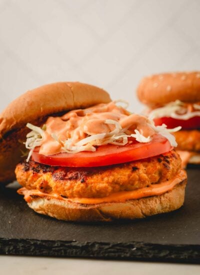 Spicy chicken burgers on a black surface.