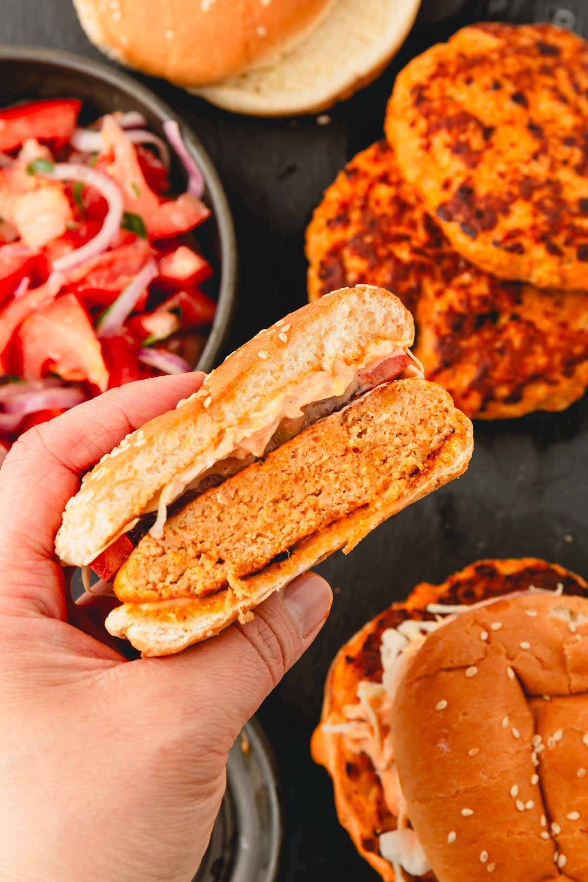 A hand is holding half of the spicy chicken burger patty.