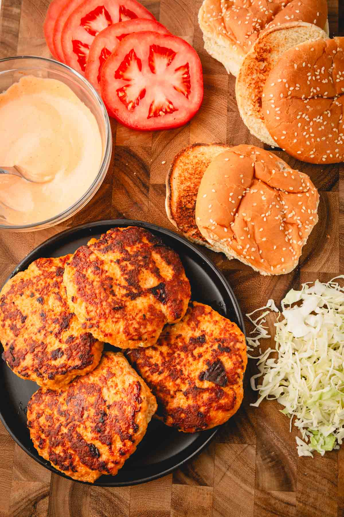 A board with ingredients to build spicy chicken burgers.