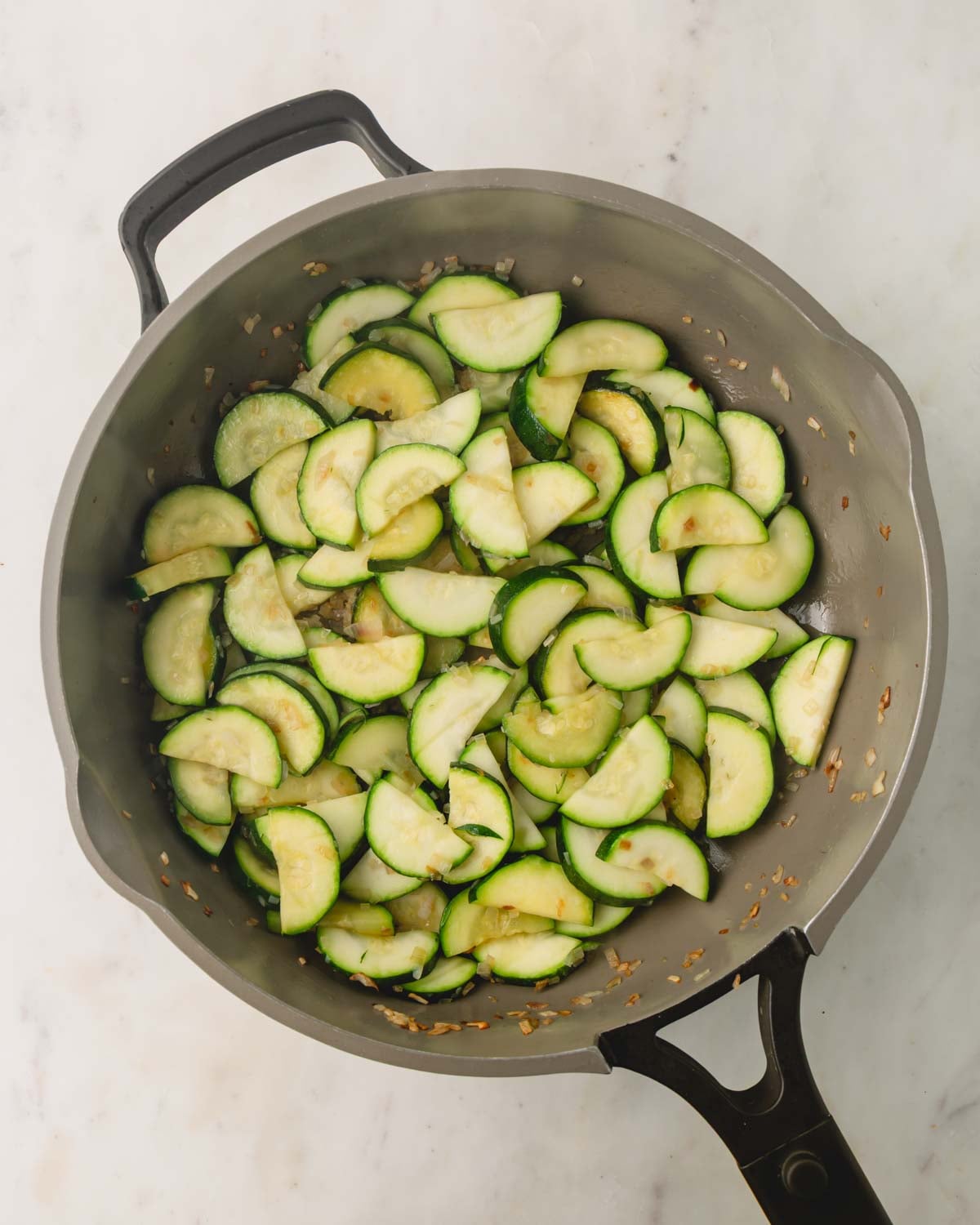 Shallot and zucchini are finished cooking in a large skillet.