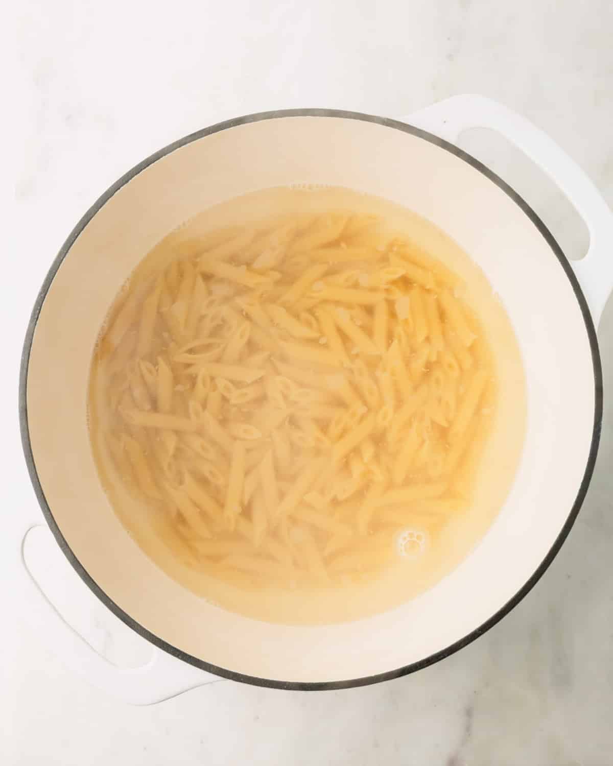 Penne boiling in a large white pot.