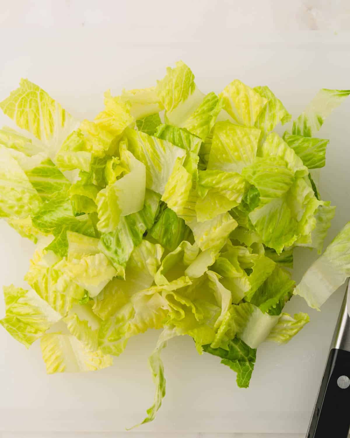 Chopped romaine on a white cutting board.
