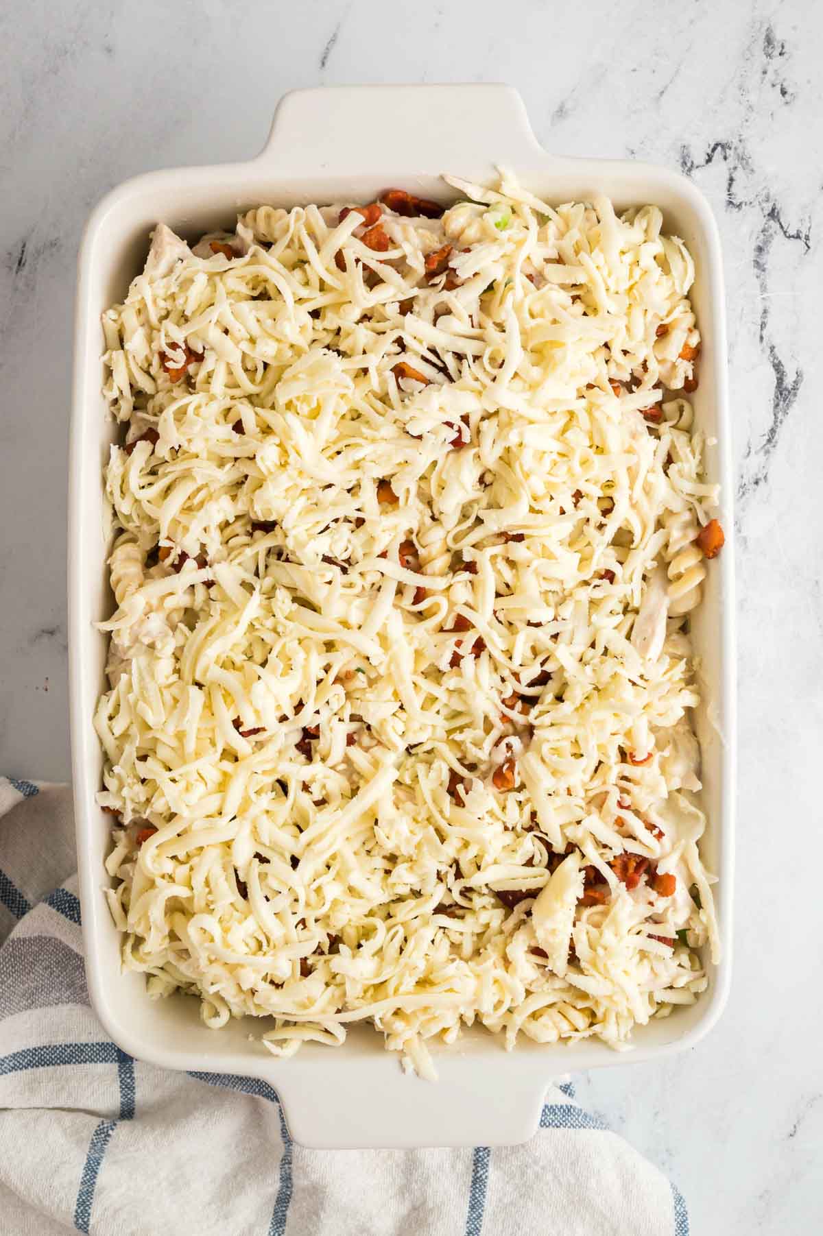 Shredded cheese is added to the top of the chicken bacon ranch casserole.