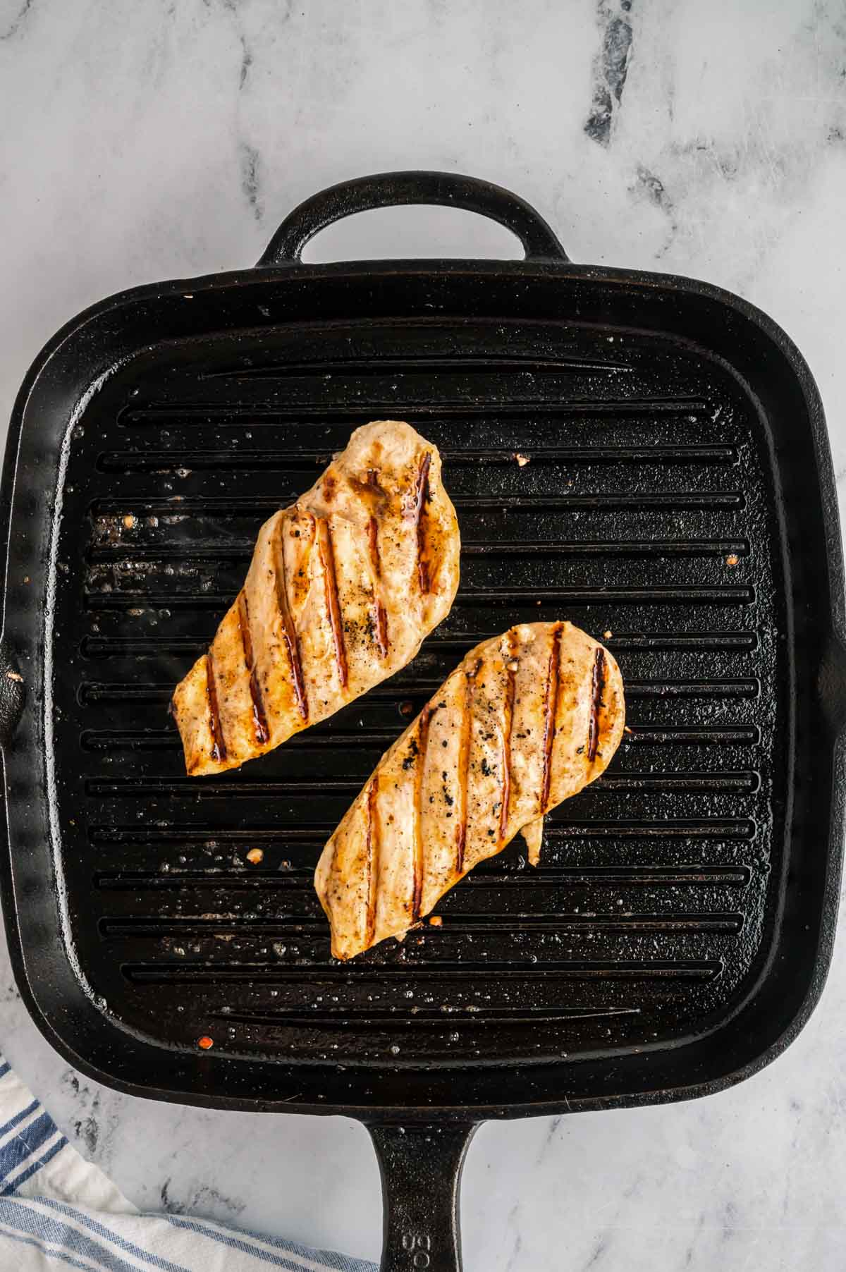 Chicken breasts grilling on a grill pan.