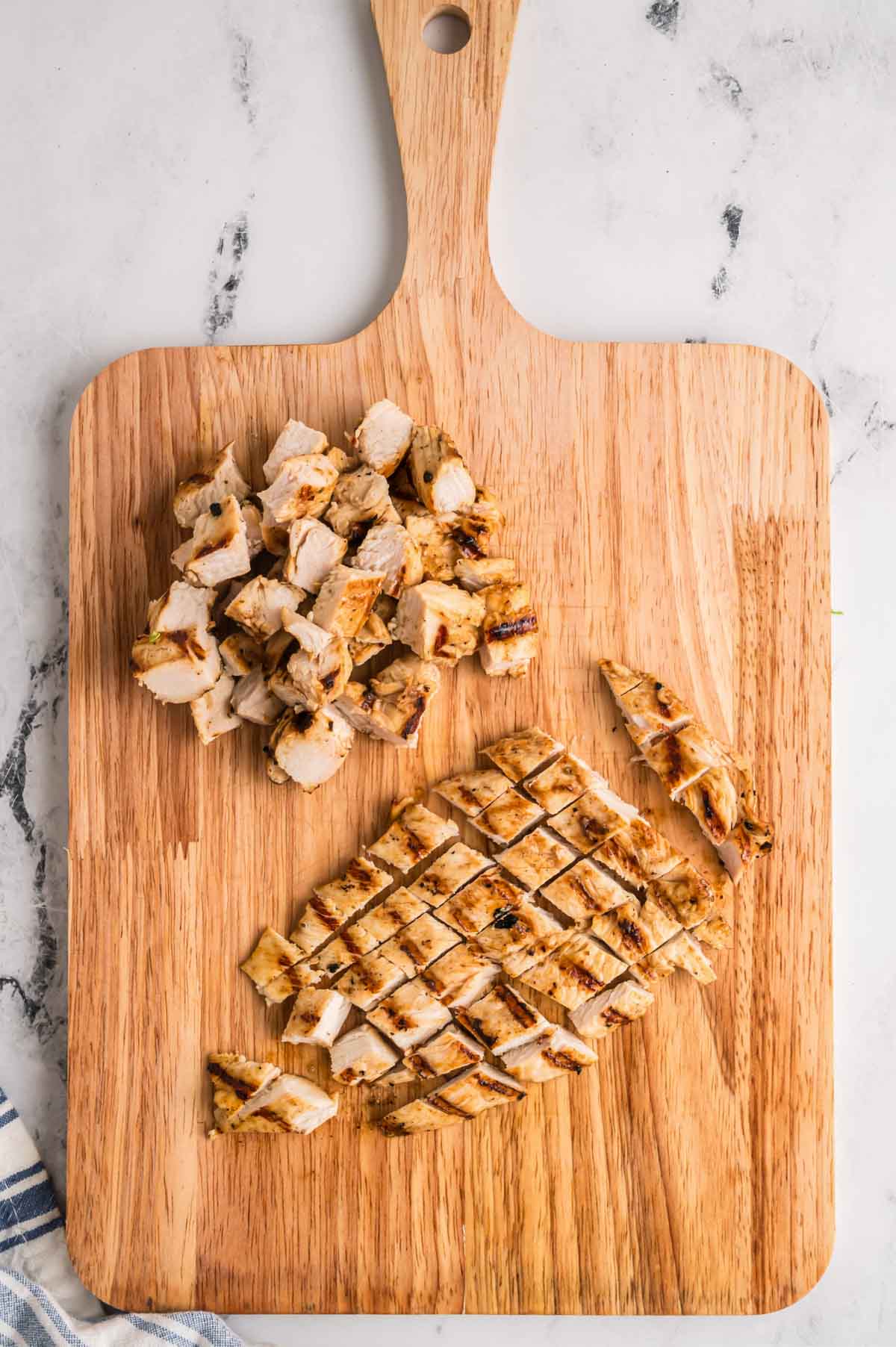 Chicken breasts cut on a wooden cutting board.