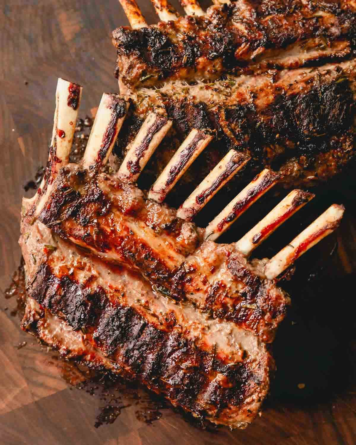 Two grilled racks of lamb on a cutting board.