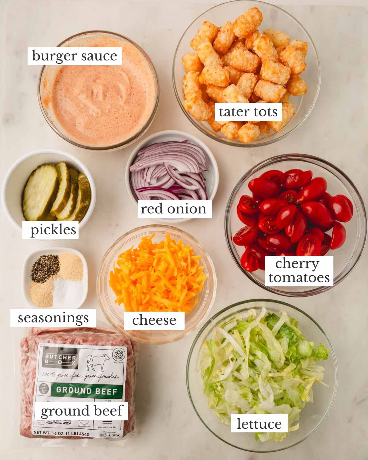 Ingredients for burger bowl laid out in individual bowls on a white counter.