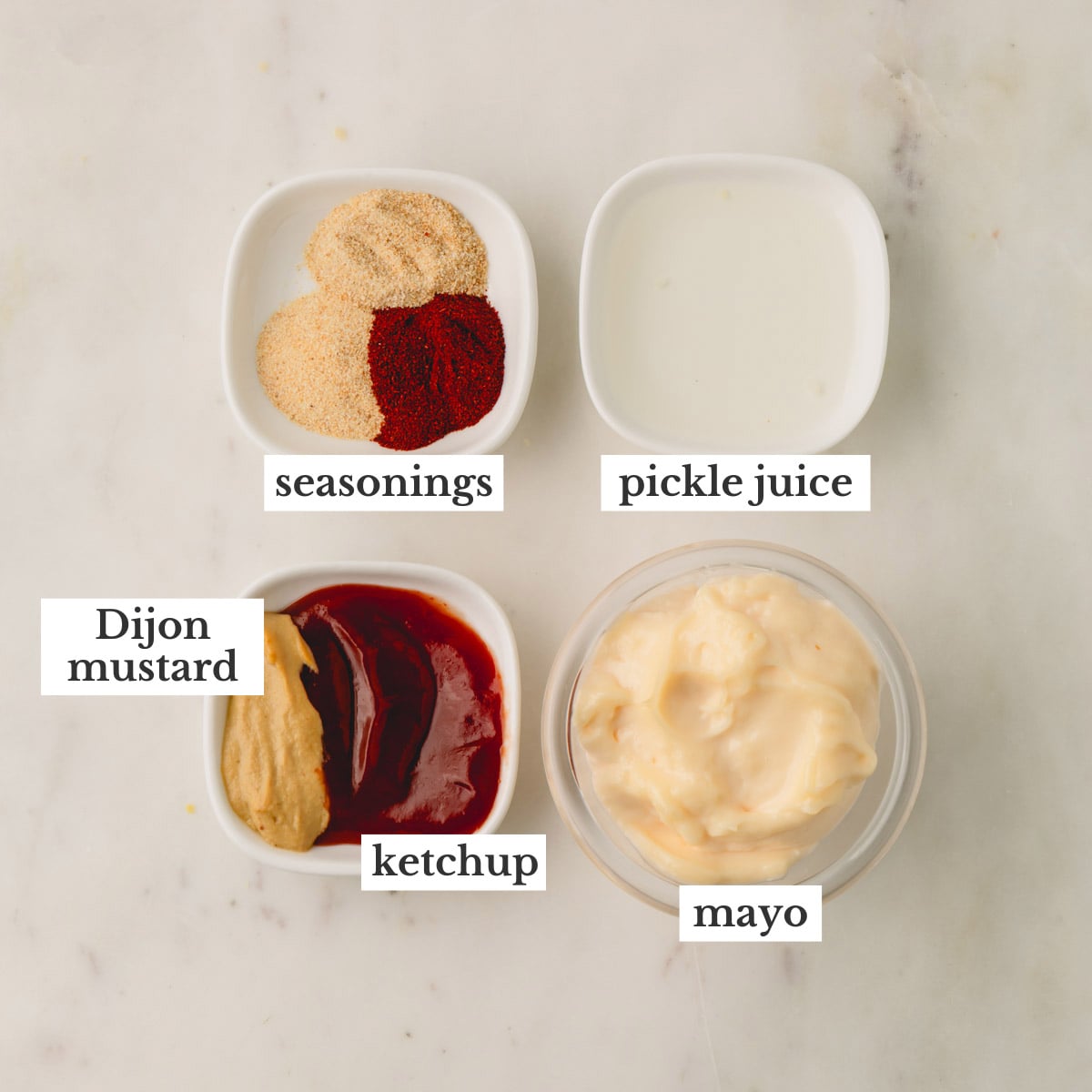 Ingredients for burger sauce in individual dishes on a white counter.
