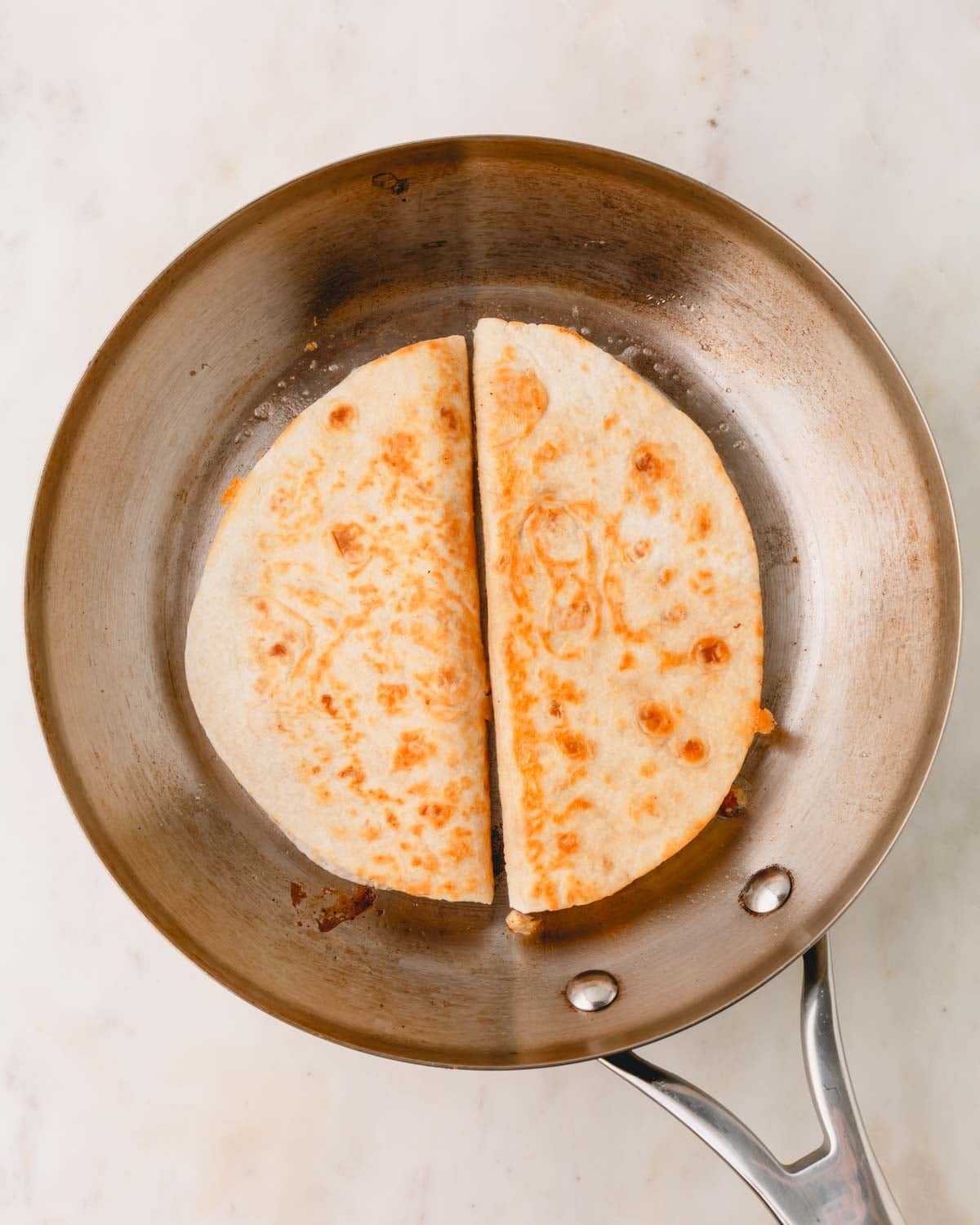 The chicken bacon ranch quesadillas are flipped in the skilled and cooking on the second side.