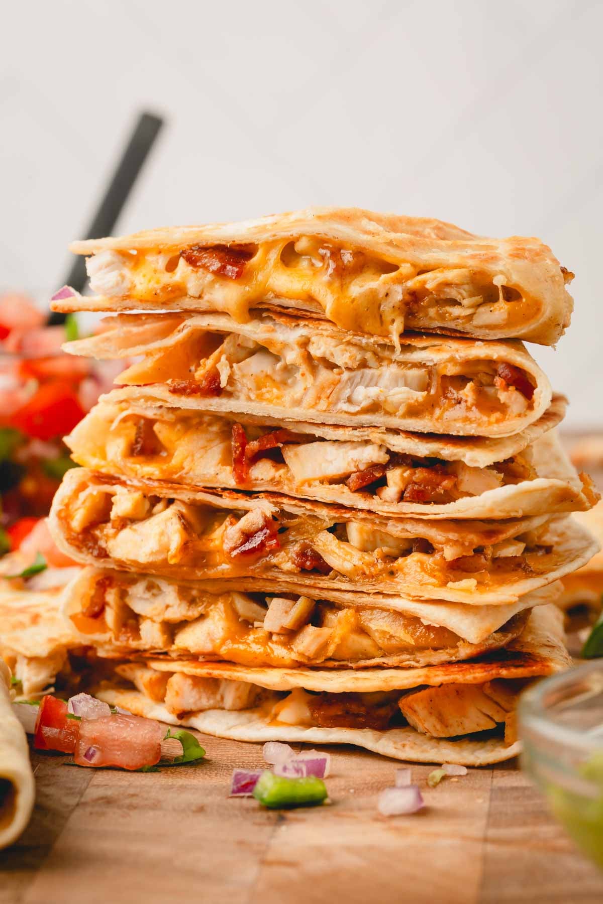 A stack of chicken bacon ranch quesadilla wedges on a cutting board.