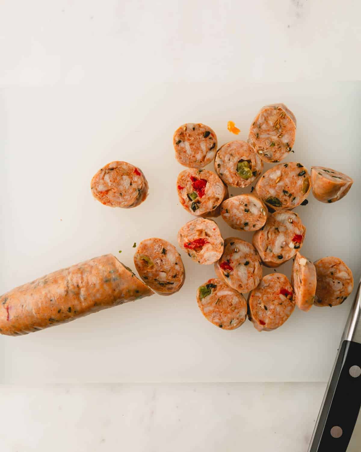 Thinly sliced Italian chicken sausage on a cutting board.