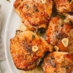 Garlic butter chicken thighs on a white plate.