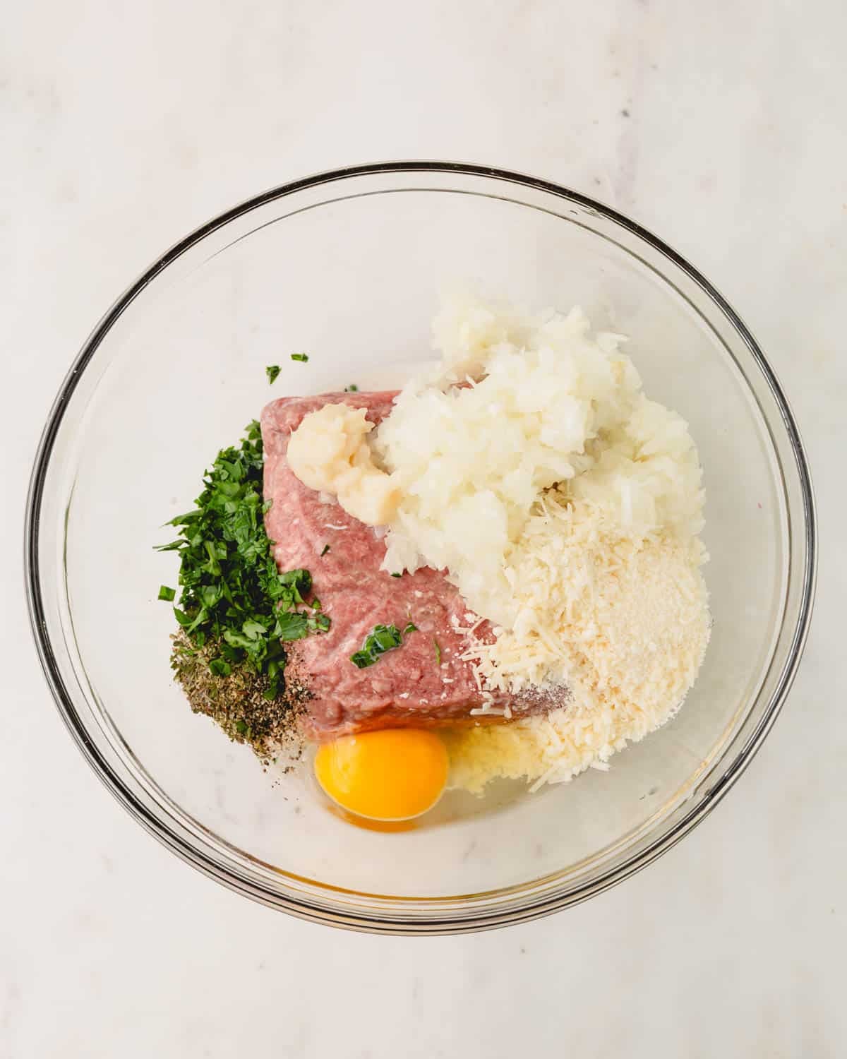 A glass bowl with the ingredients for gluten-free meatballs.
