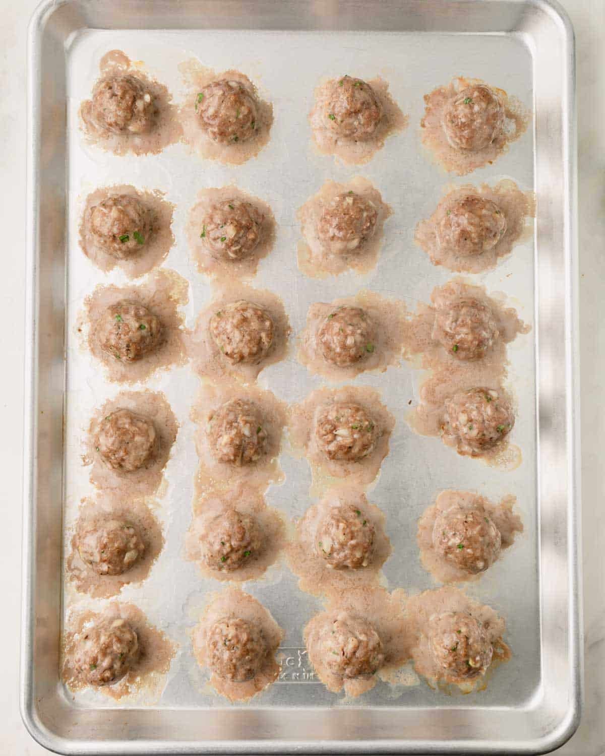 Baked beef meatballs on a baking sheet.