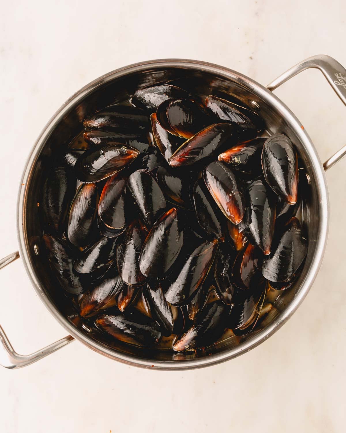 Mussels added to the large saute pan for pasta with mussels.