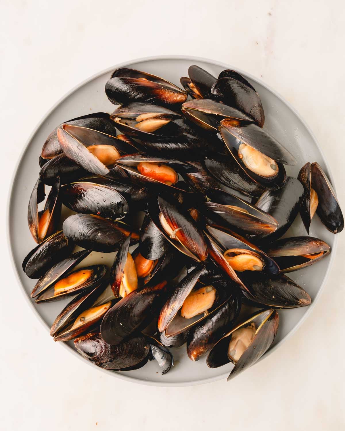 Steamed mussels are removed to a plate.