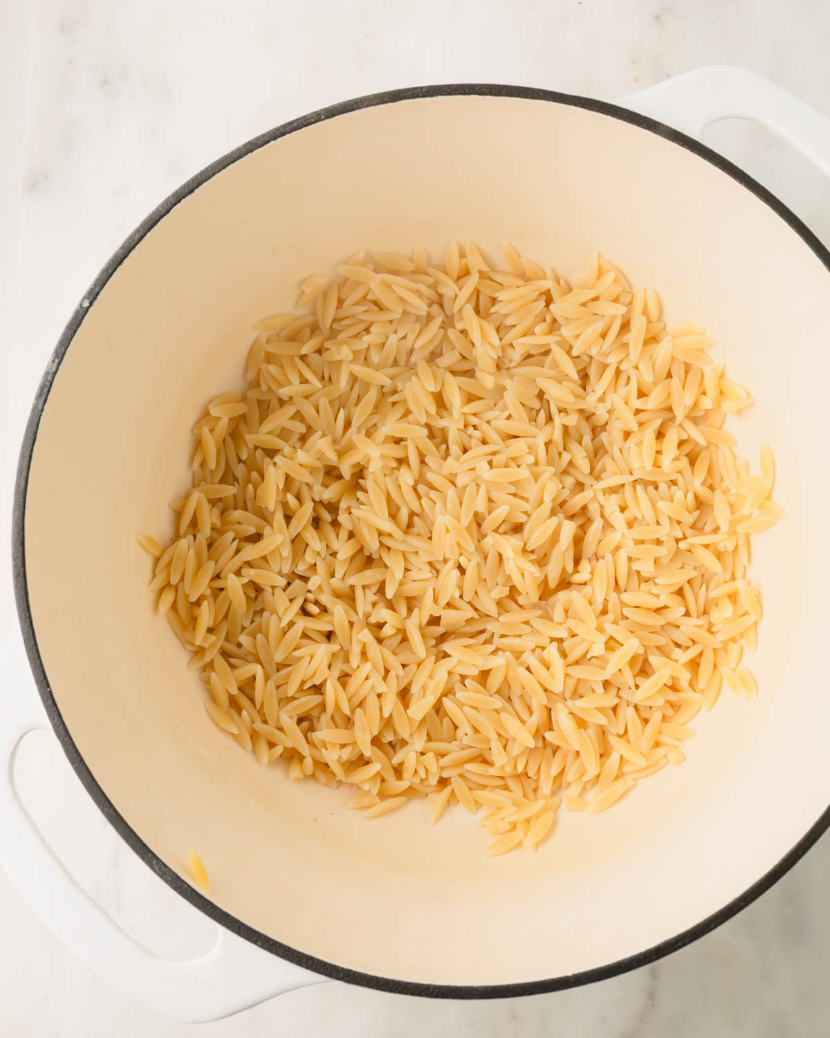Orzo cooking in a large white pot.