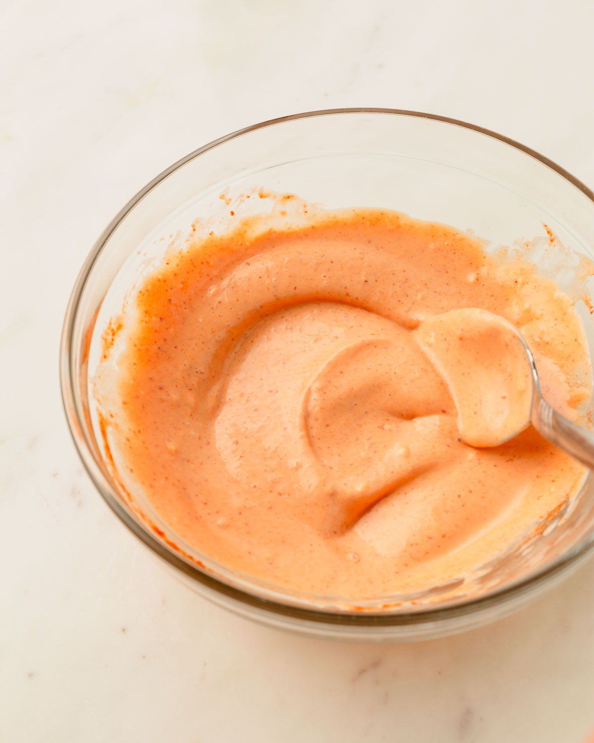 Mixed sriracha mayo in a glass bowl.