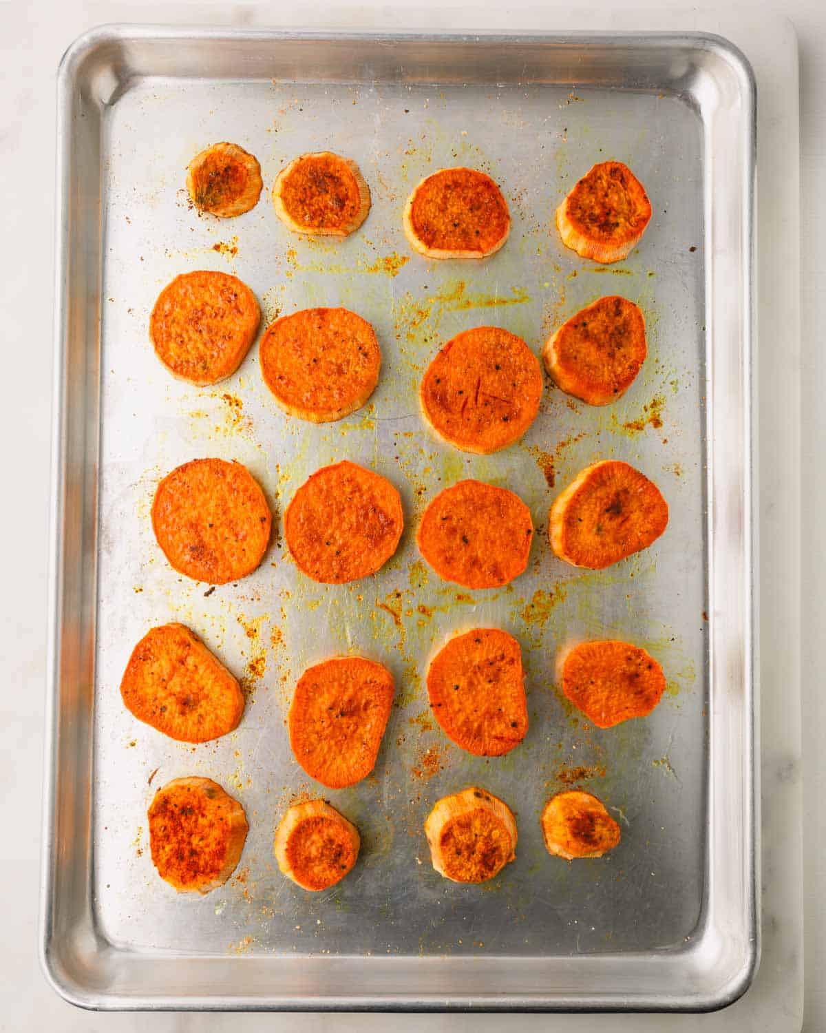 Baked sliced sweet potatoes on a baking sheet.