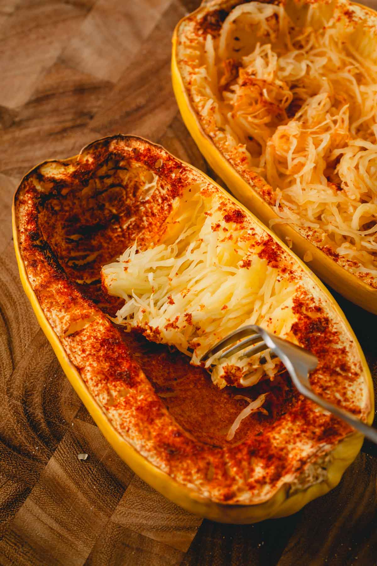 A fork is fluffing the inside of the spaghetti squash.