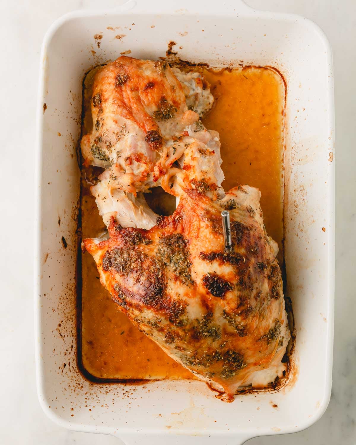 The turkey breast is roasted in a white baking dish.