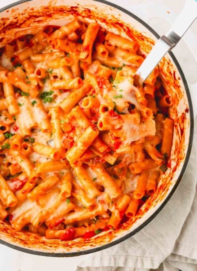 Baked vegetarian ziti in a white skillet with a serving spoon.