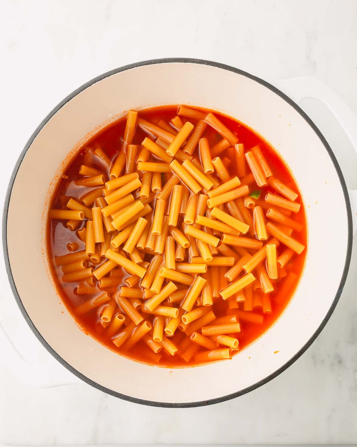 Ziti noodles are added with water to the marinara sauce and vegetables.