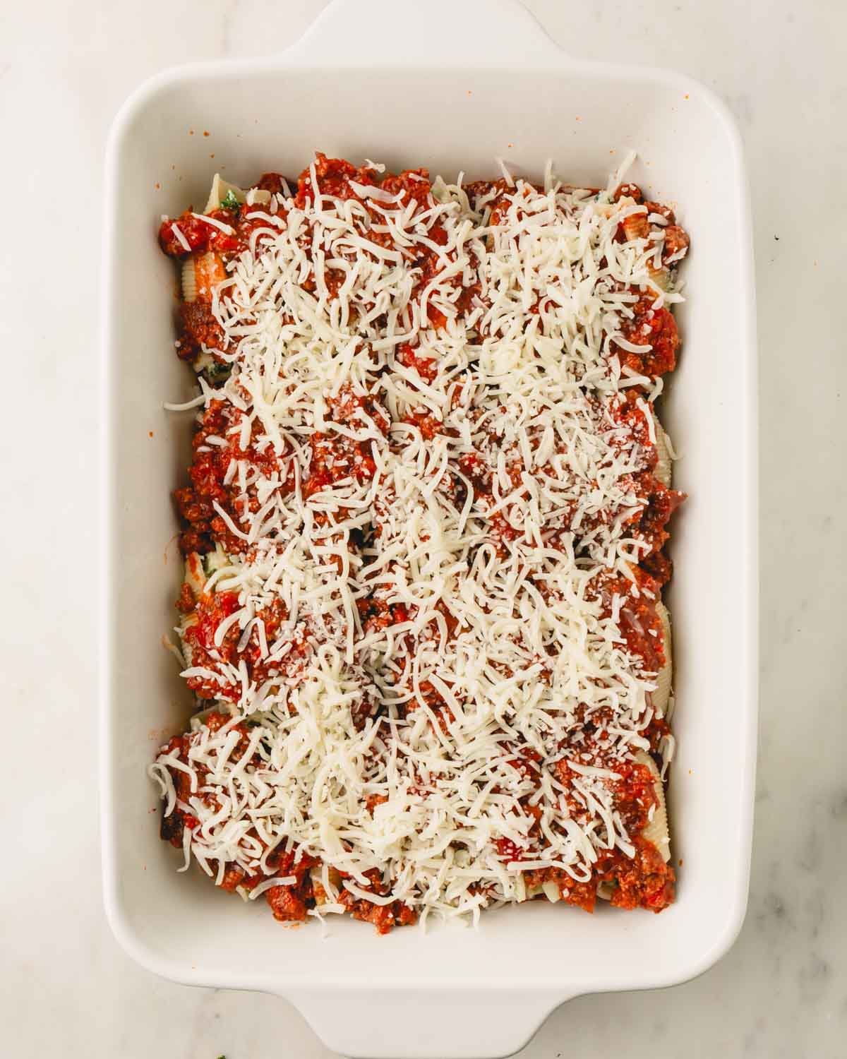 Shredded mozzarella cheese on top of the stuffed shell mixture.