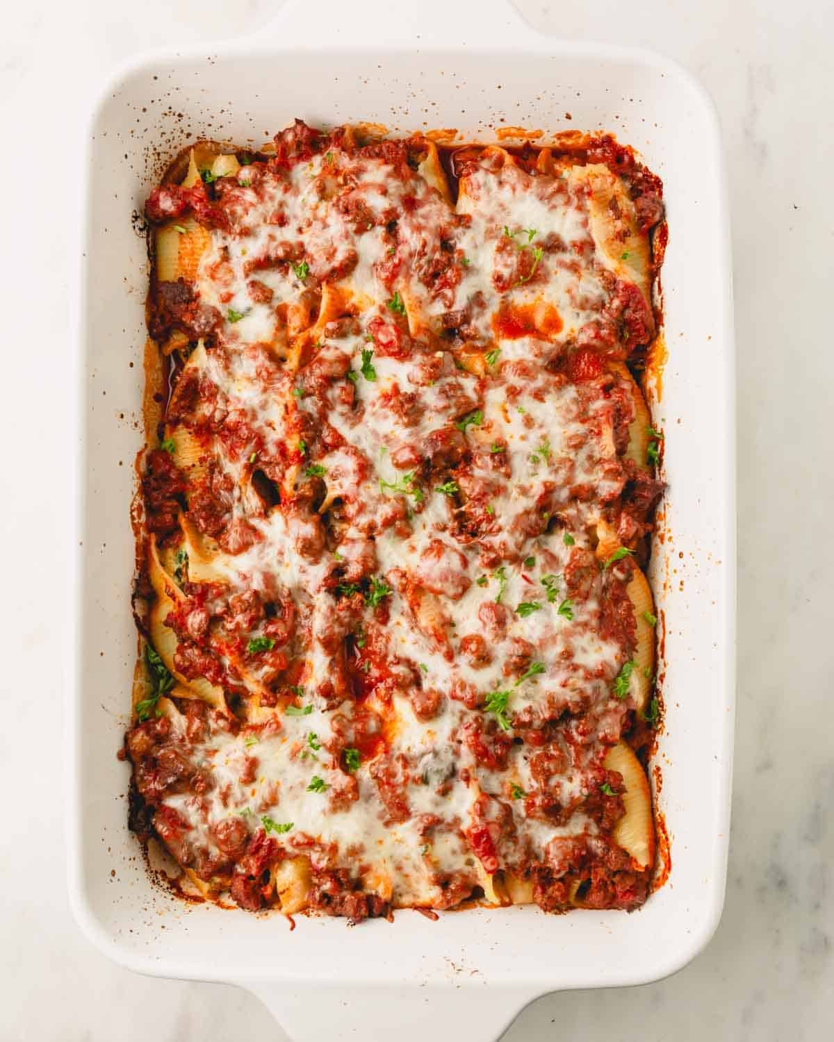 Beef and ricotta stuffed shells in a white casserole dish.