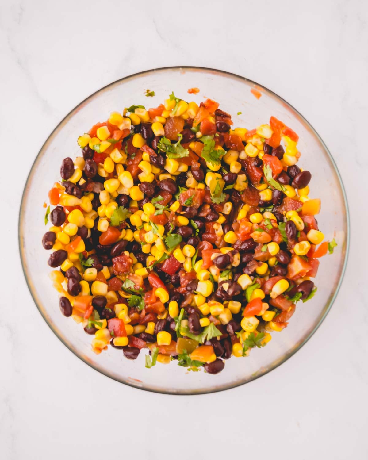 A glass bowl of mixed corn and black bean salsa.