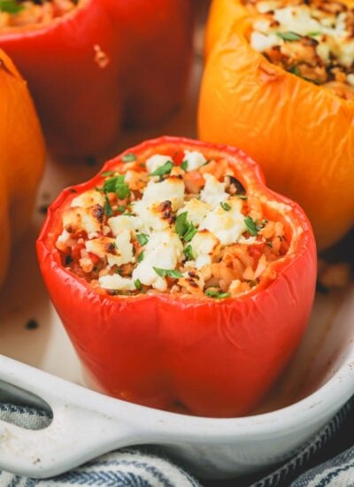 Close up image of Greek stuffed peppers in a baking dish.