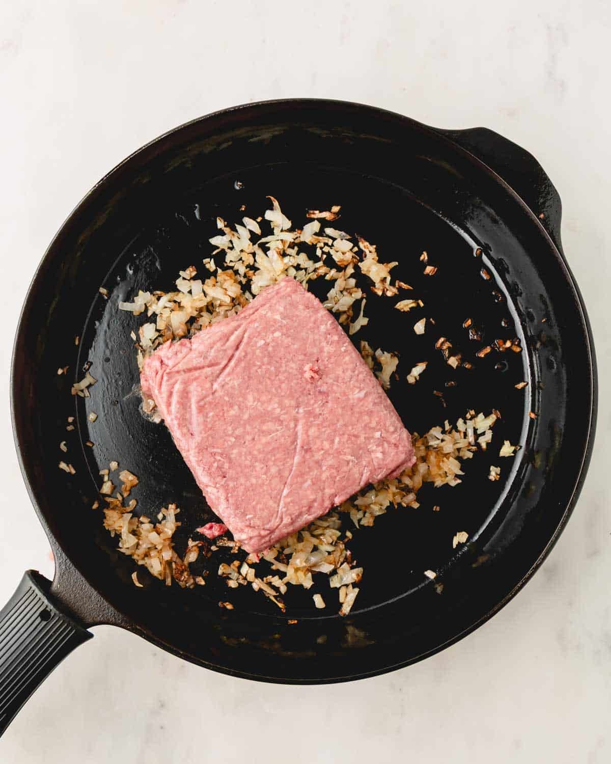 A skillet with browned onion and ground beef.