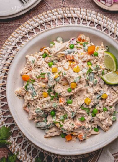 Mexican chicken salad in a beige plate with limes.