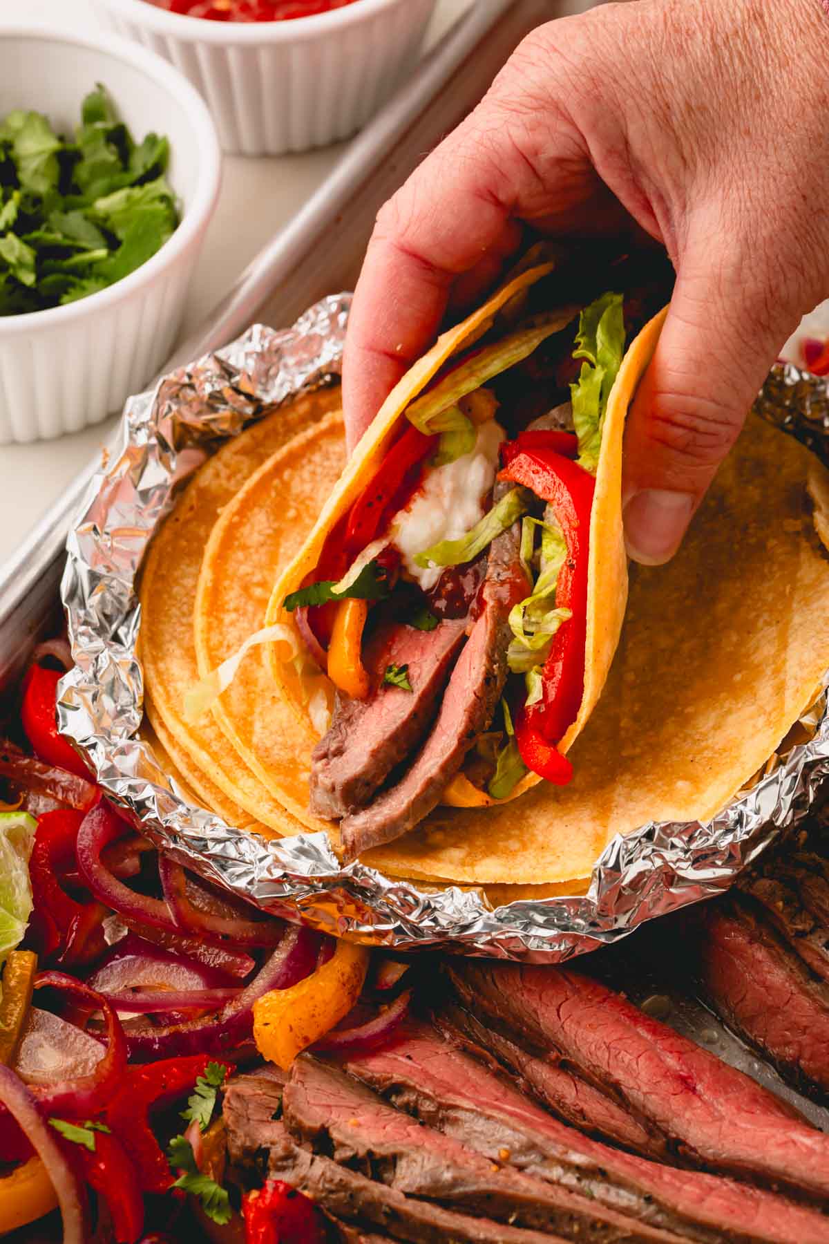 A hand holding a sheet pan steak fajita.