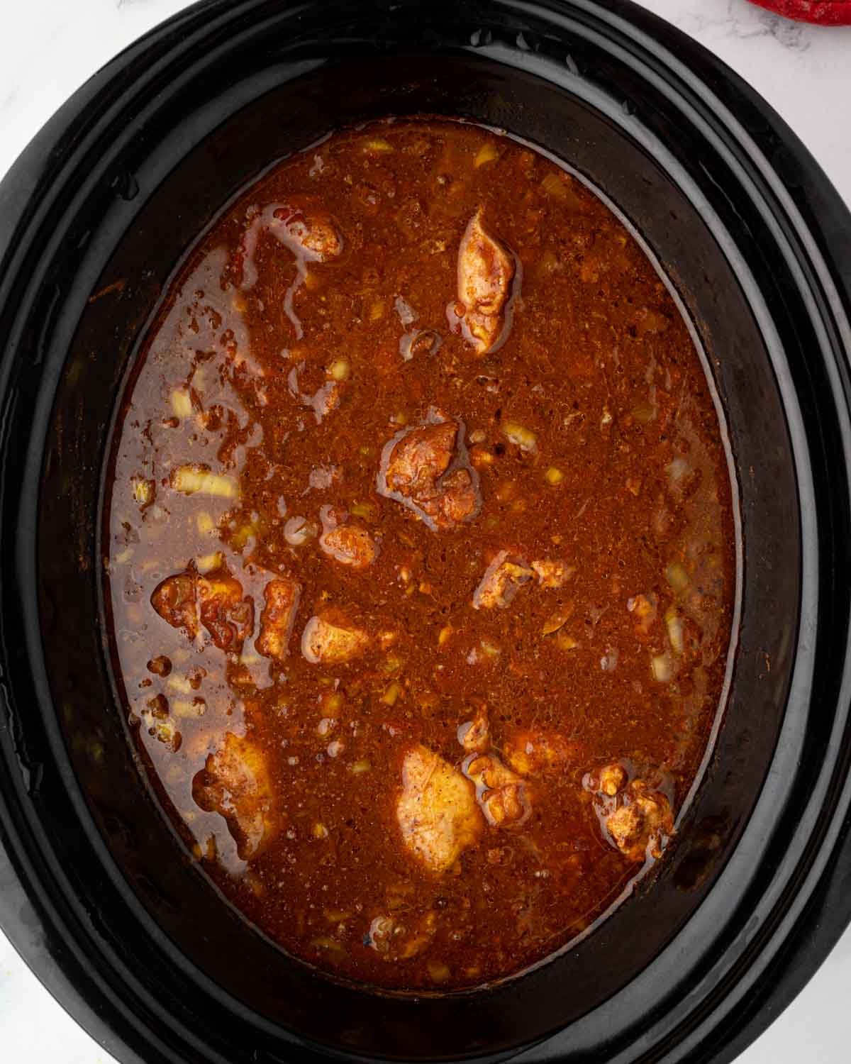 Slow cooker butter chicken is cooked in the bowl of a slow cooker.