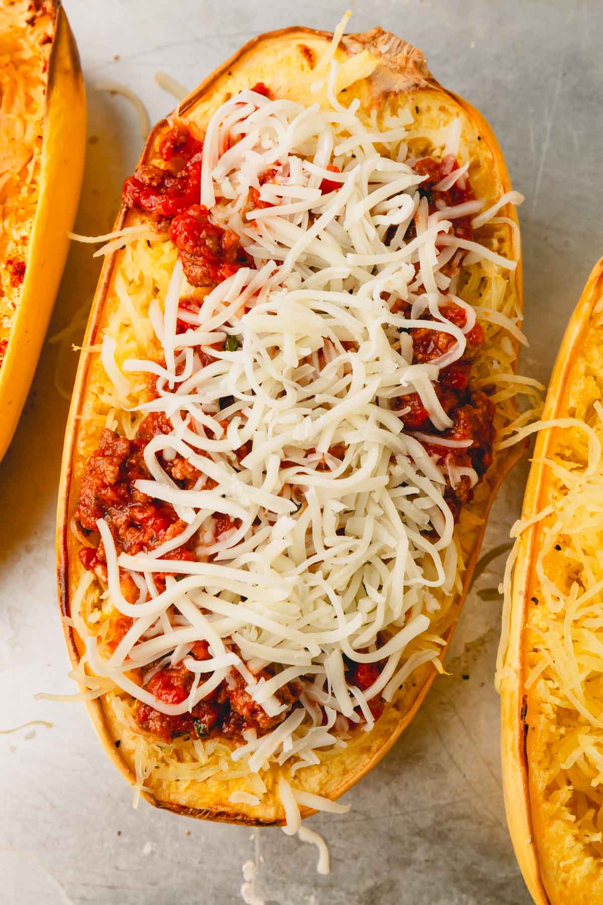 A spaghetti squash half with meat sauce and topped with shredded mozzarella cheese.
