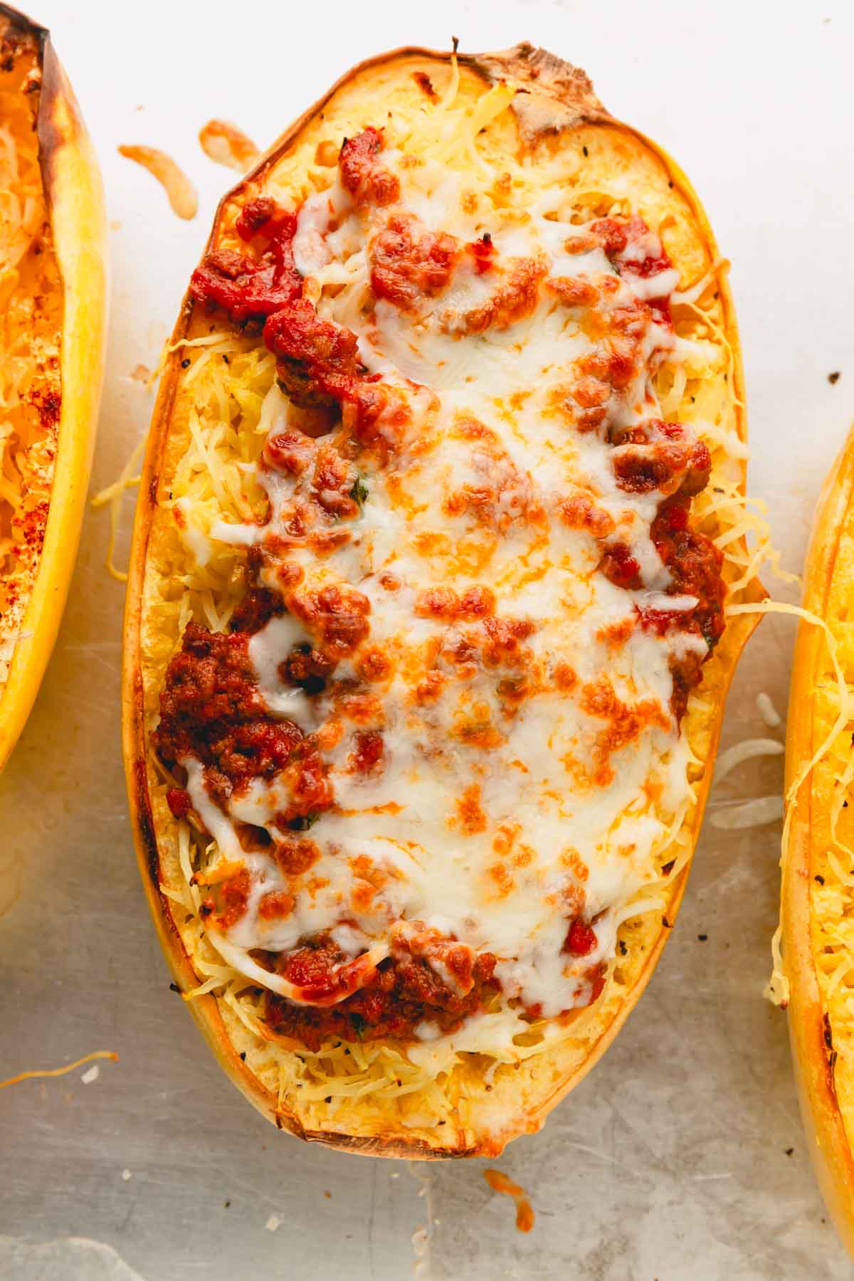 A baked spaghetti squash half with melted mozzarella cheese on top.