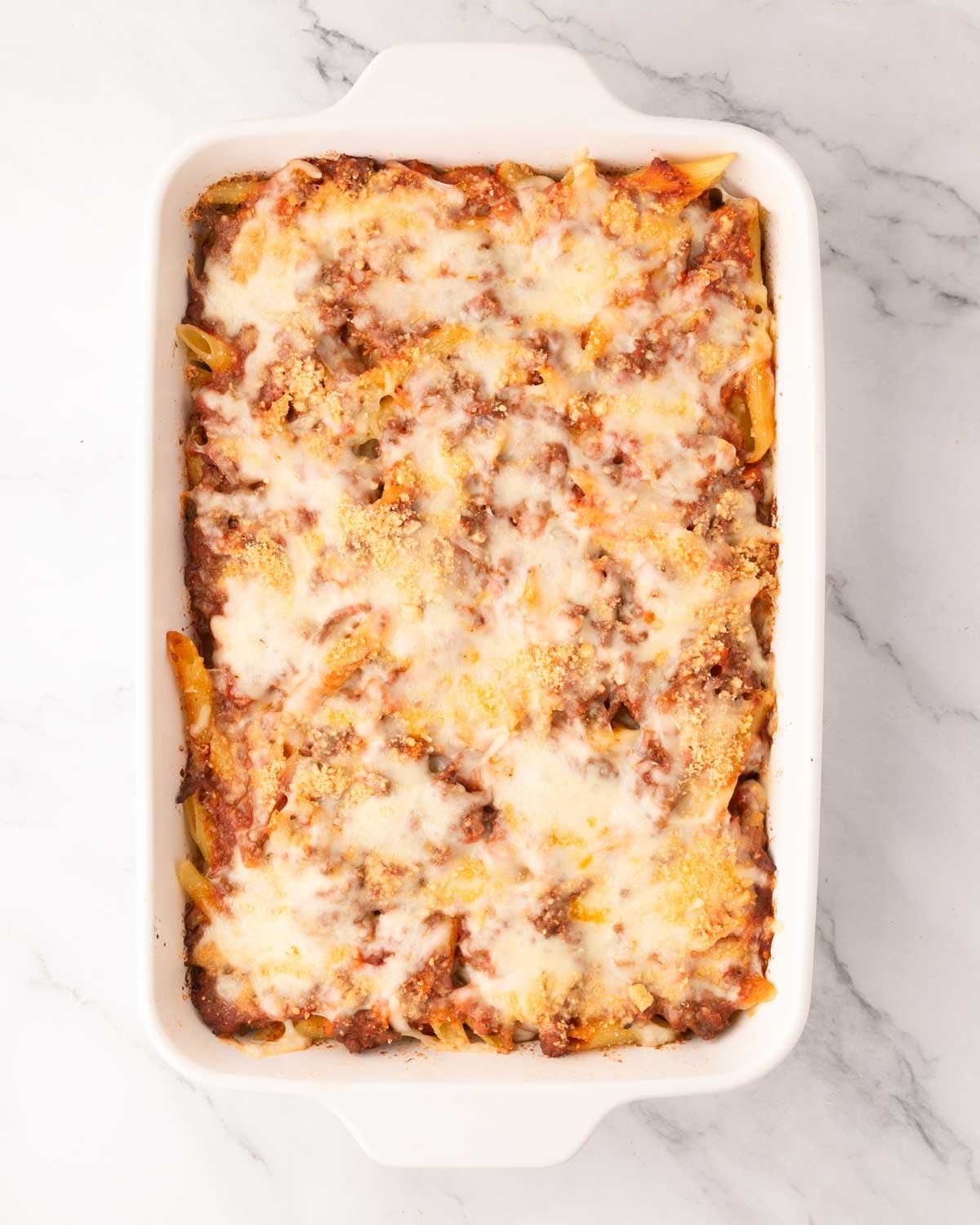 Baked pasta bolognese in a white baking dish.