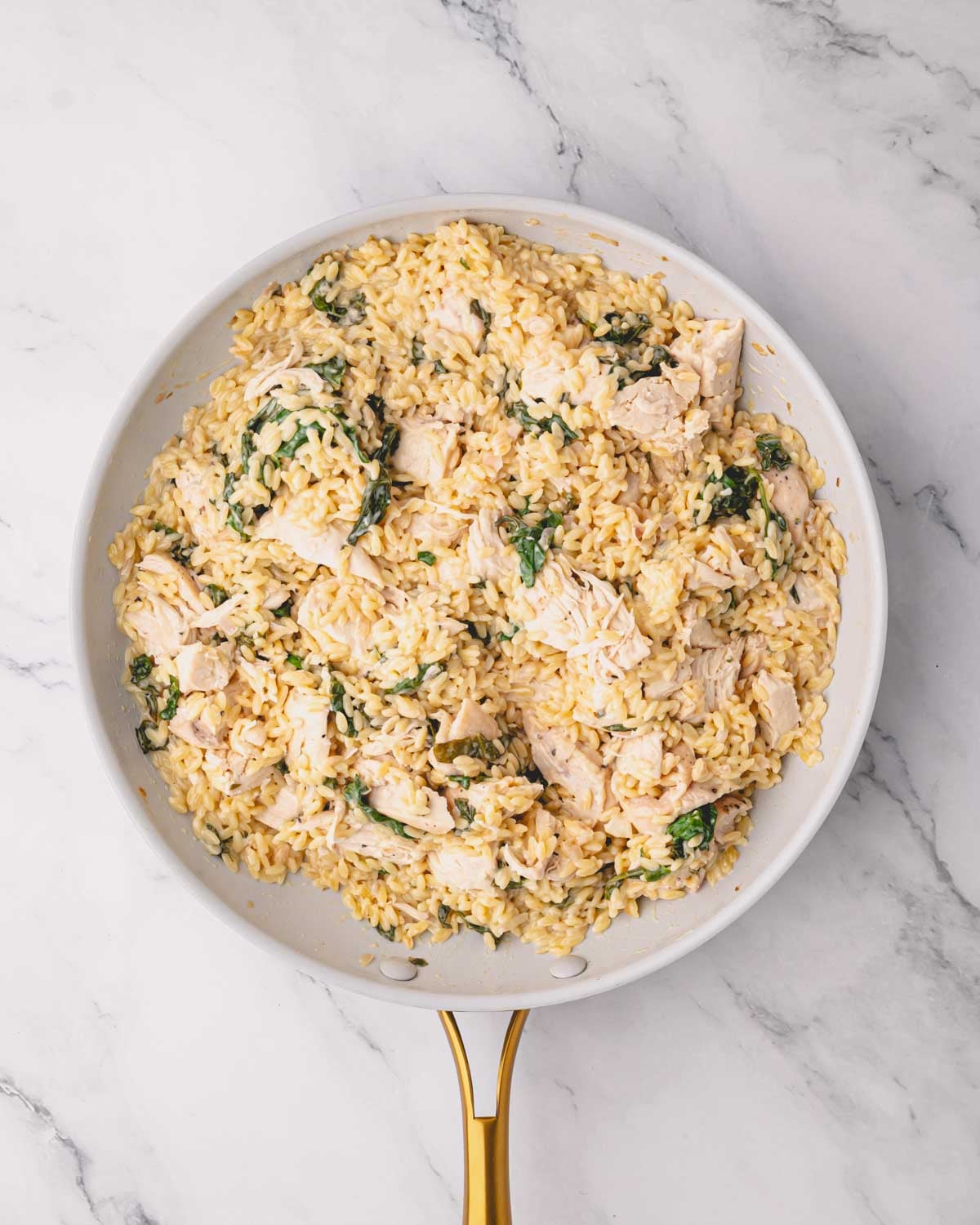 A white skillet with lemon chicken orzo.