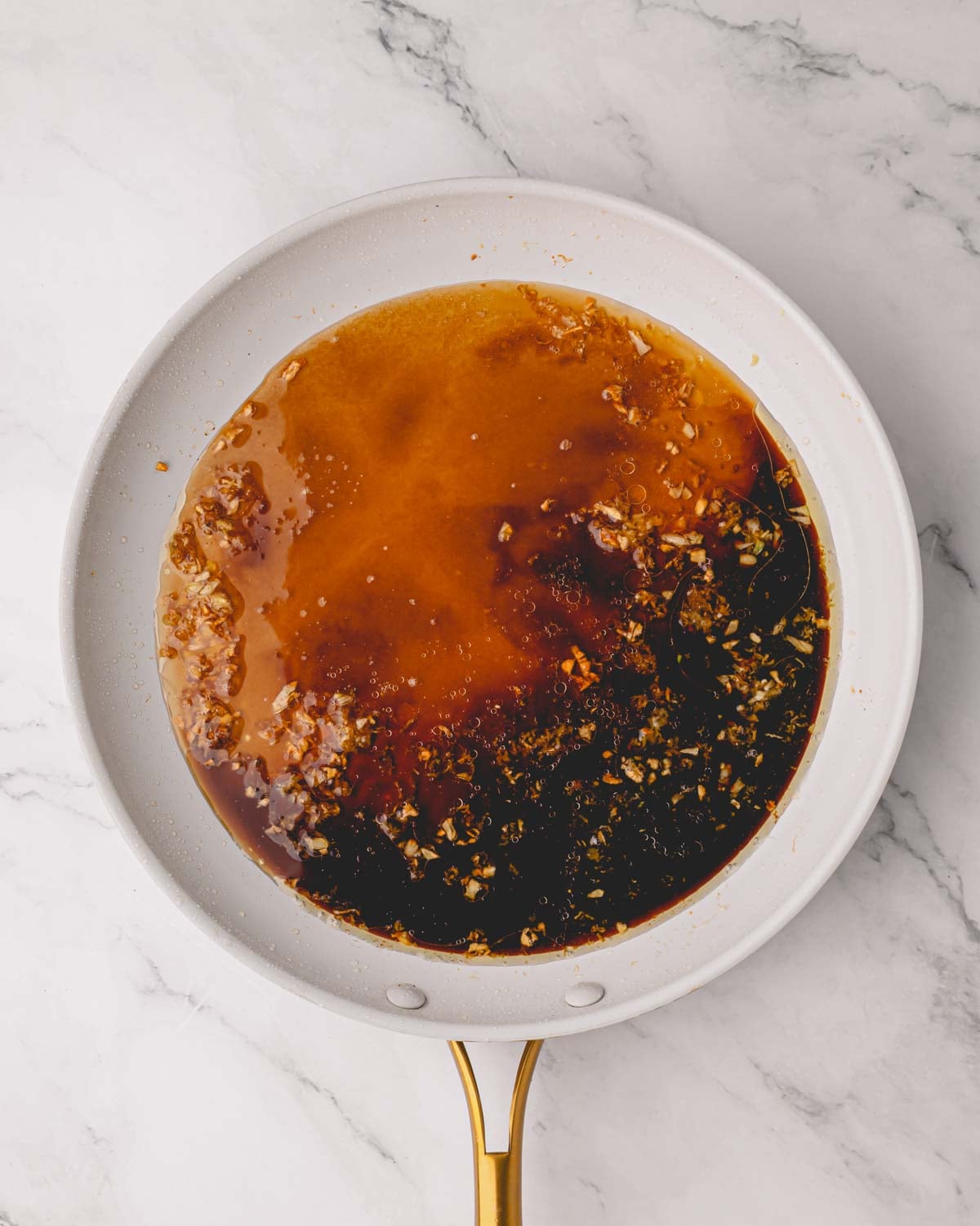 A white skillet with shoyu sauce.