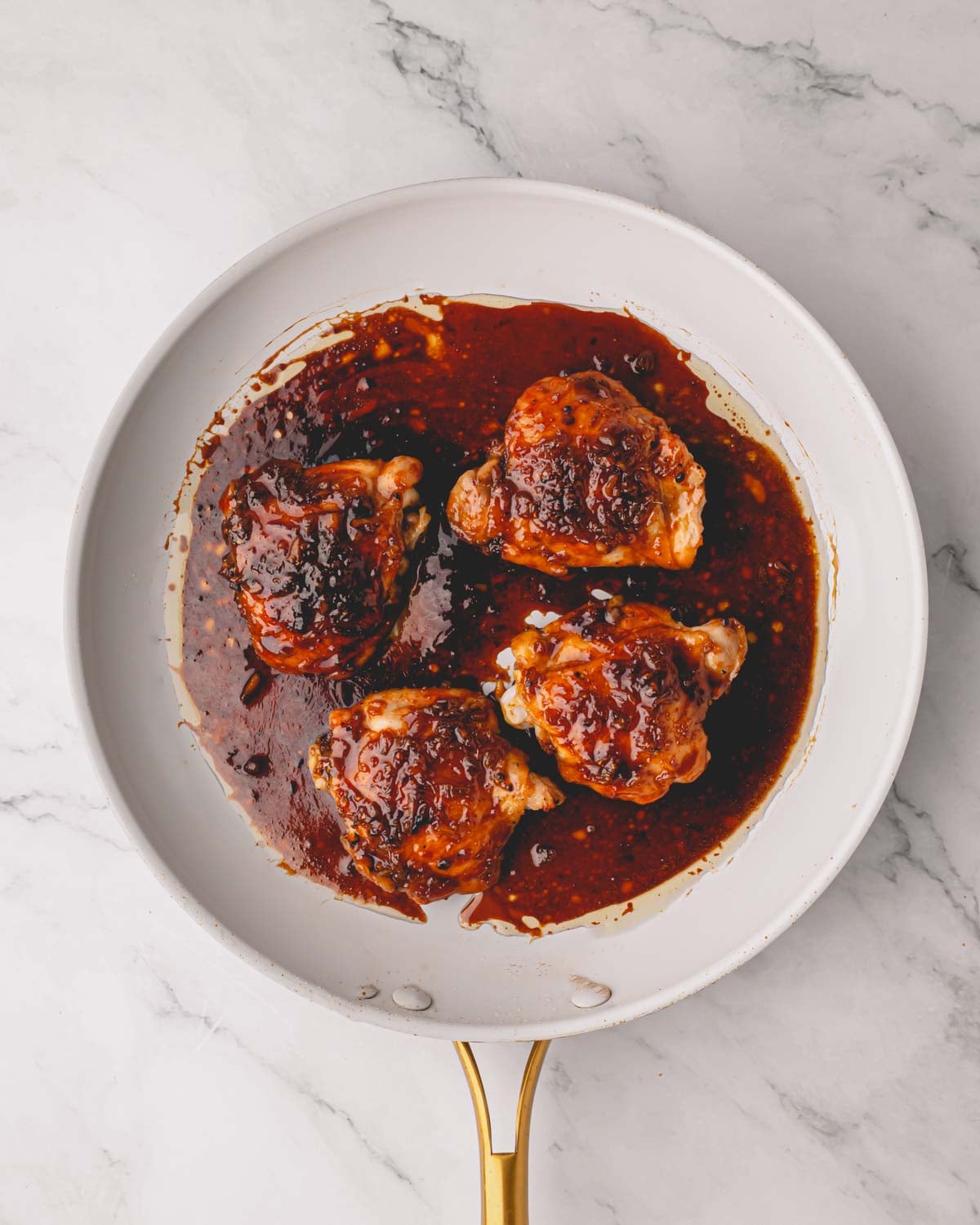 A white skillet with four shoyu chicken thighs.