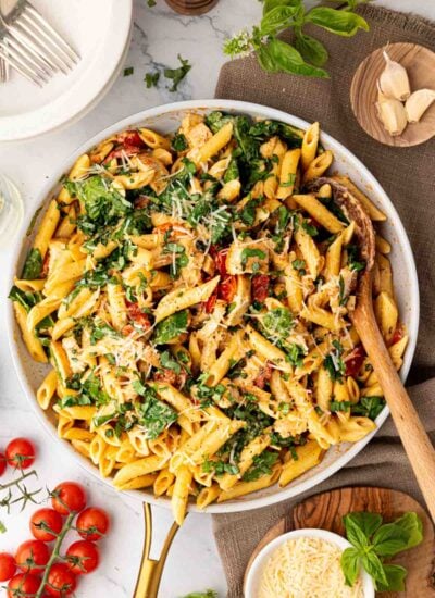 A white skillet of boursin chicken pasta with a wooden spoon.