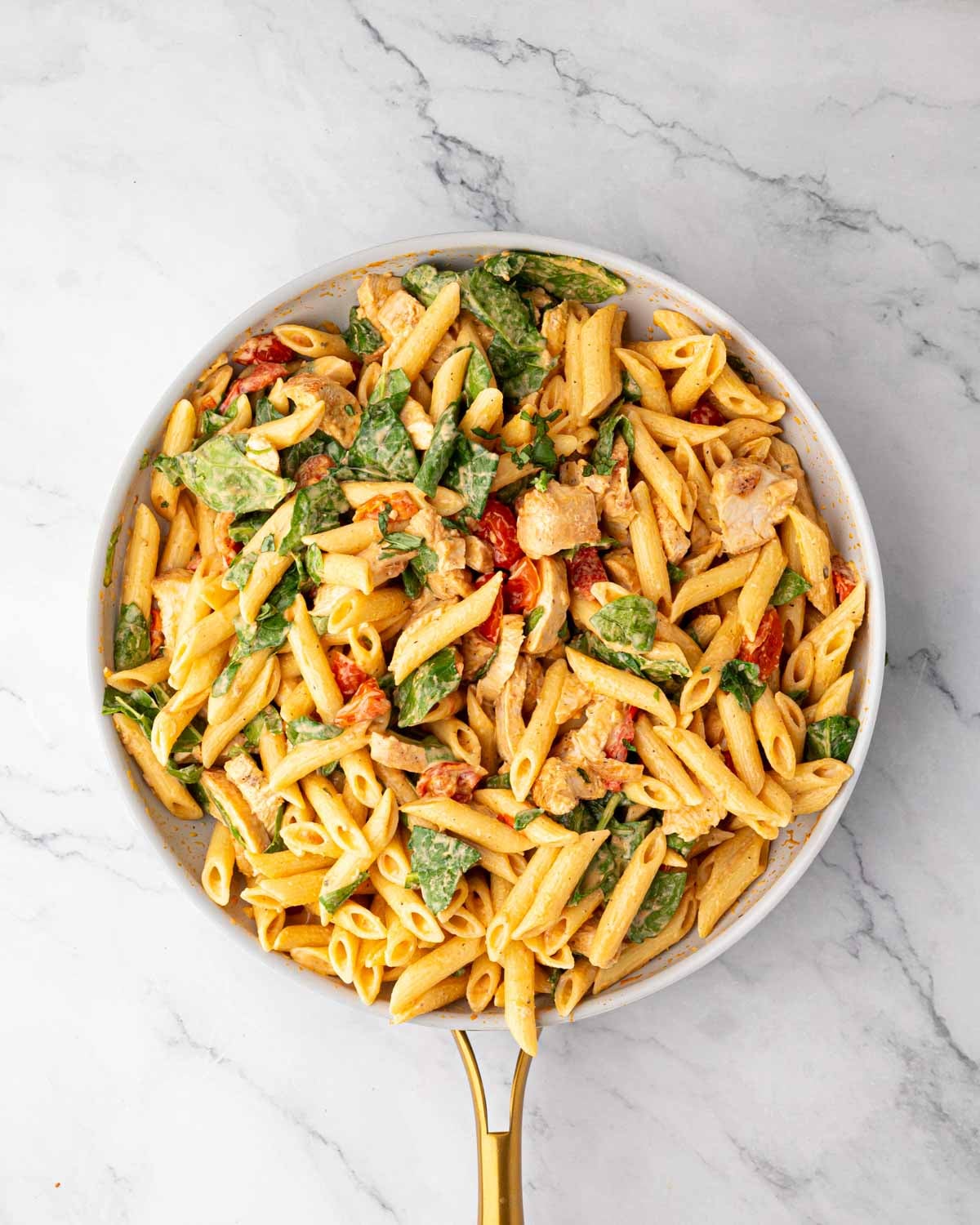 A white skillet with boursin chicken pasta stirred together.