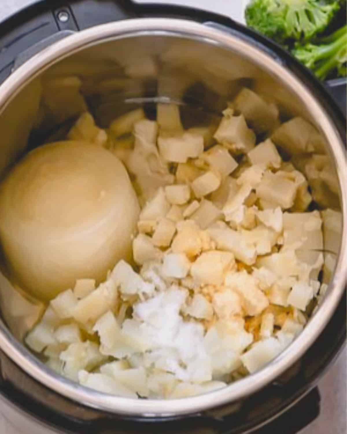 An instant pot with potatoes and frozen chicken broth.