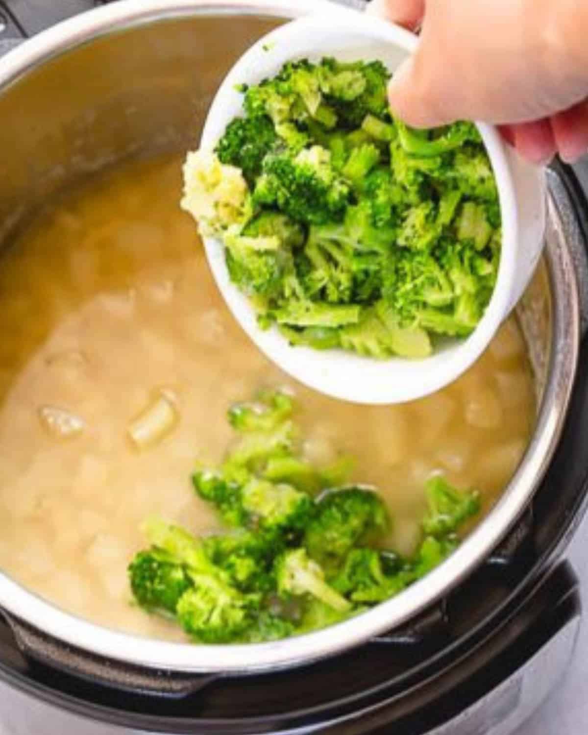 A hand adding a white bowl of broccoli florets.