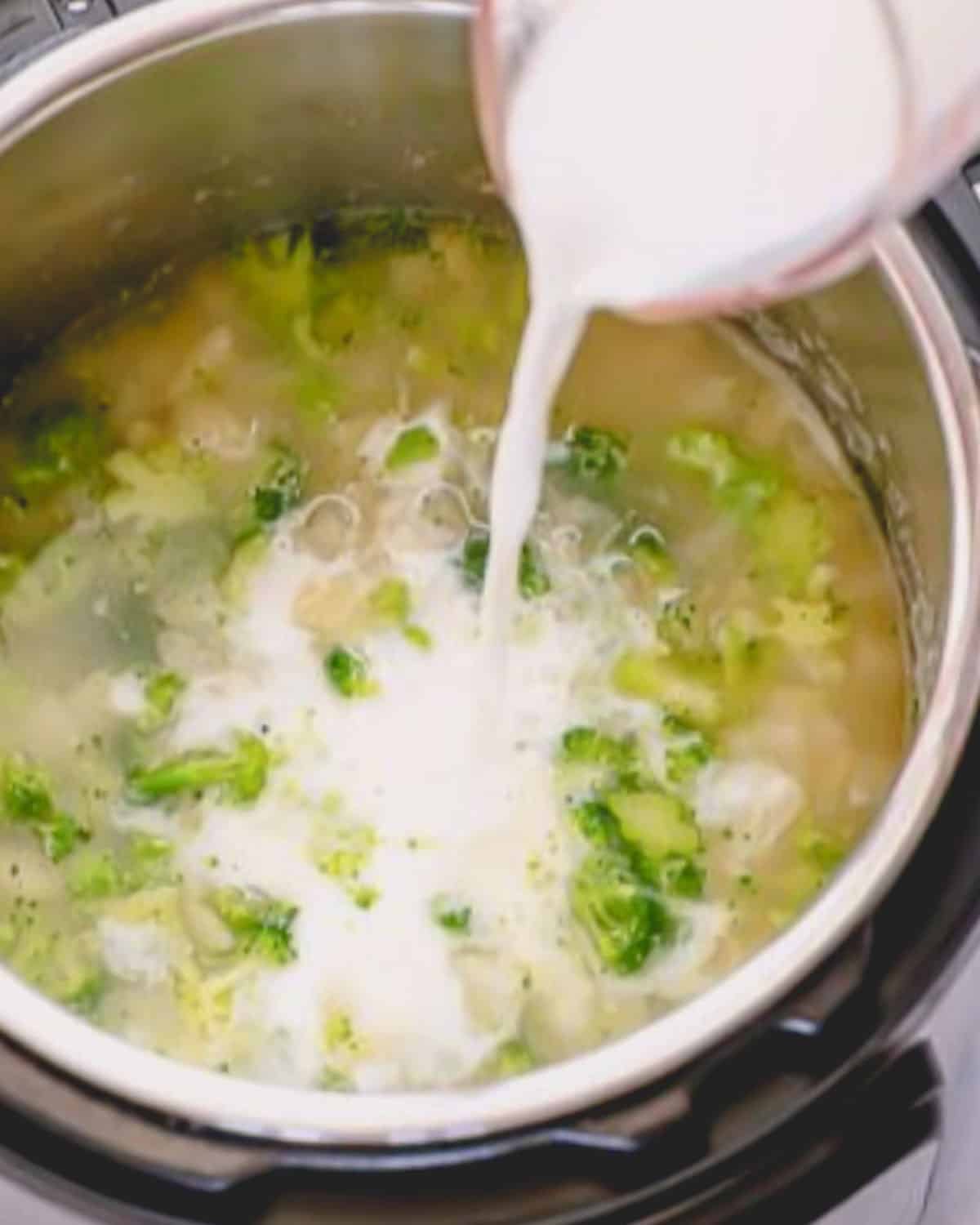 A measuring cup adding milk to the broccoli potato soup in the instant pot.