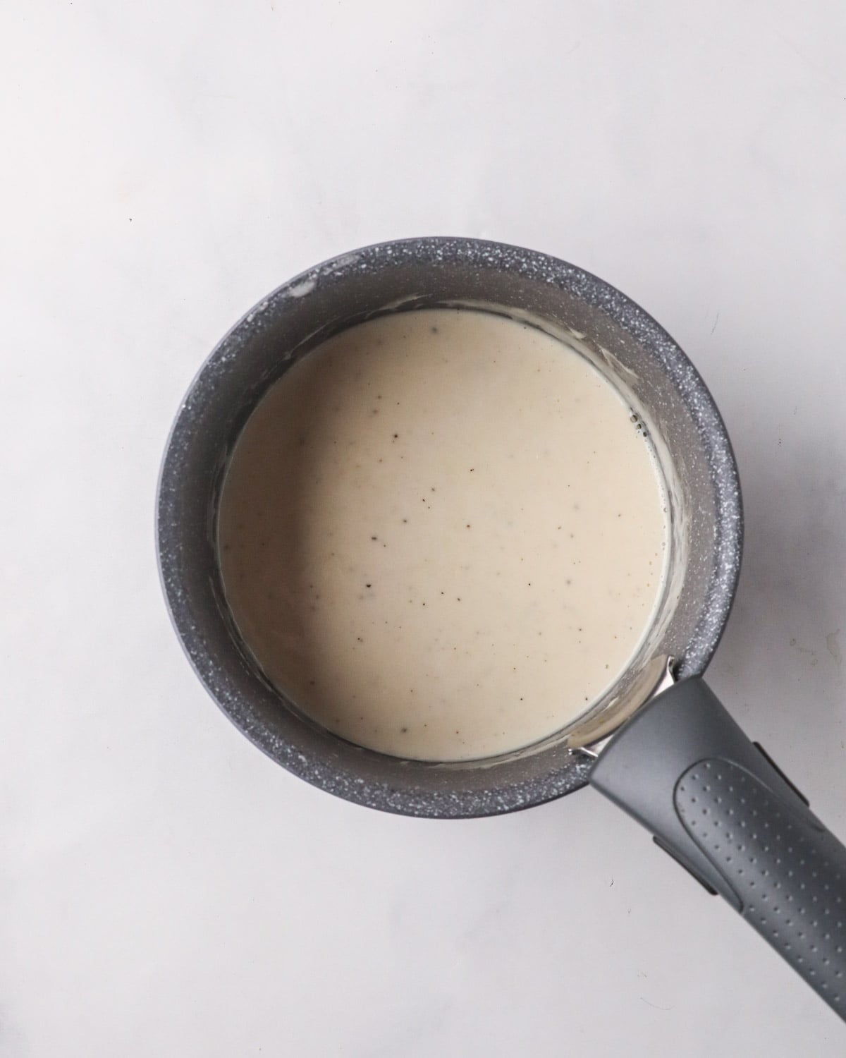 A small black saucepan with creamy mixture cooking.