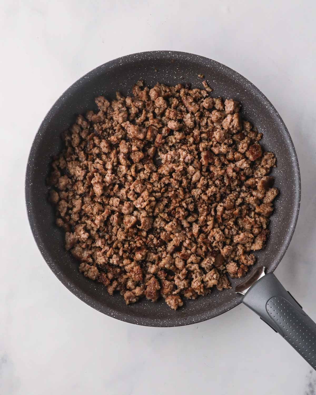 A black skillet with sausage mixture cooking.