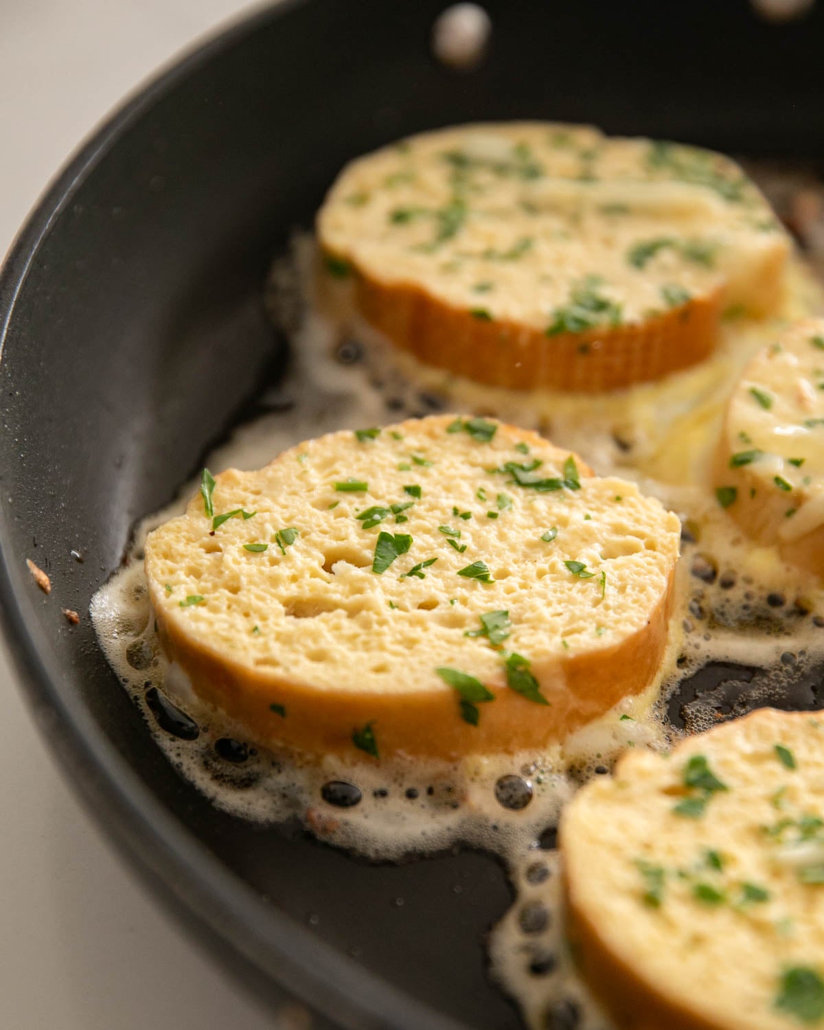 Savory french toast is cooking in a black skillet.