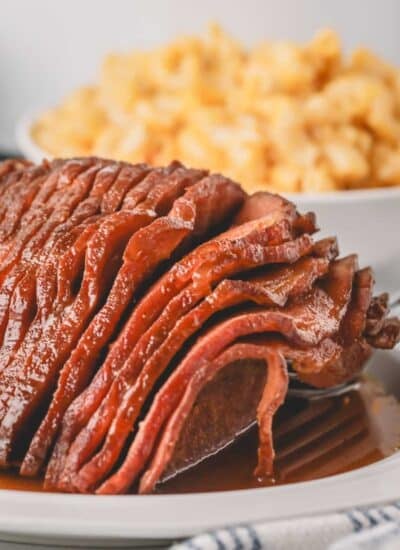 Close up of slow cooker honey glazed ham on a white plate.
